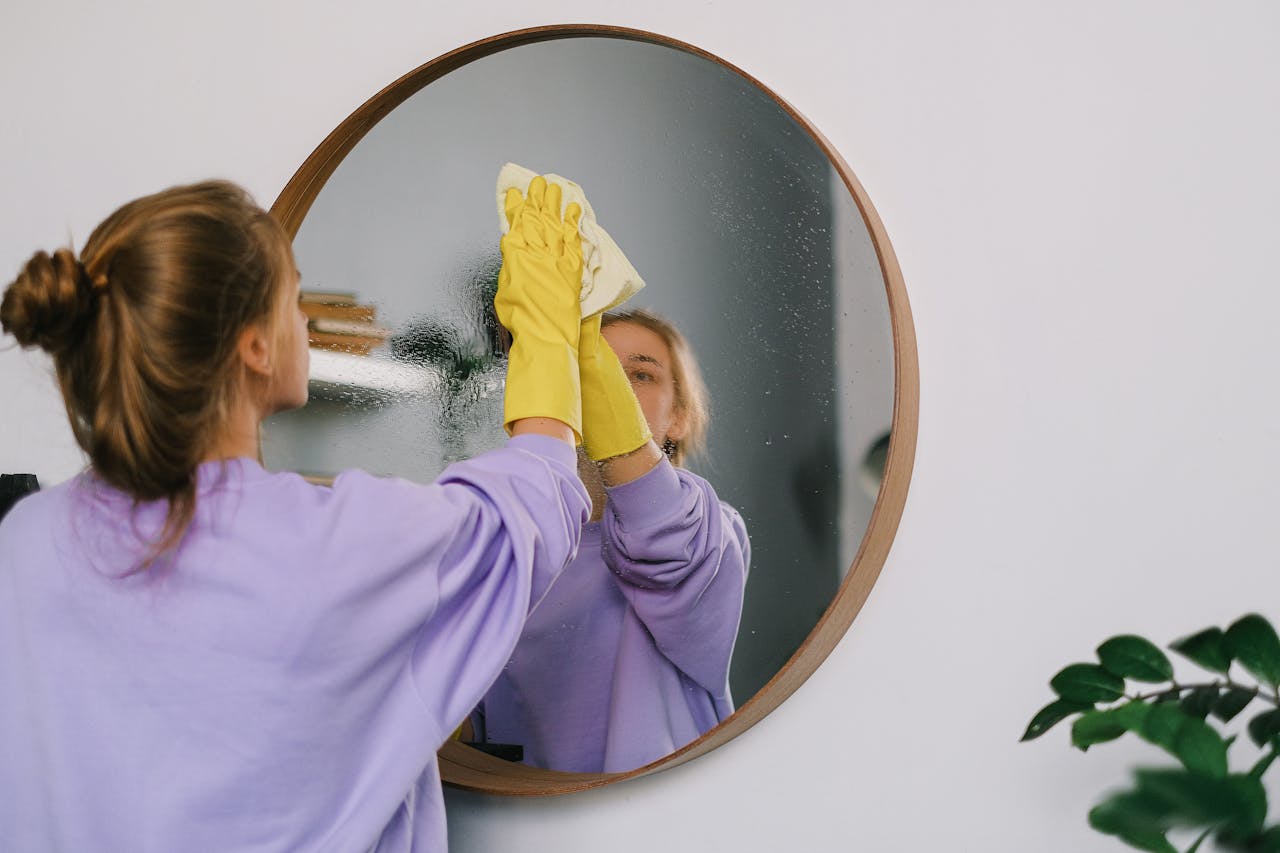 maid cleaning a mirror on the wall